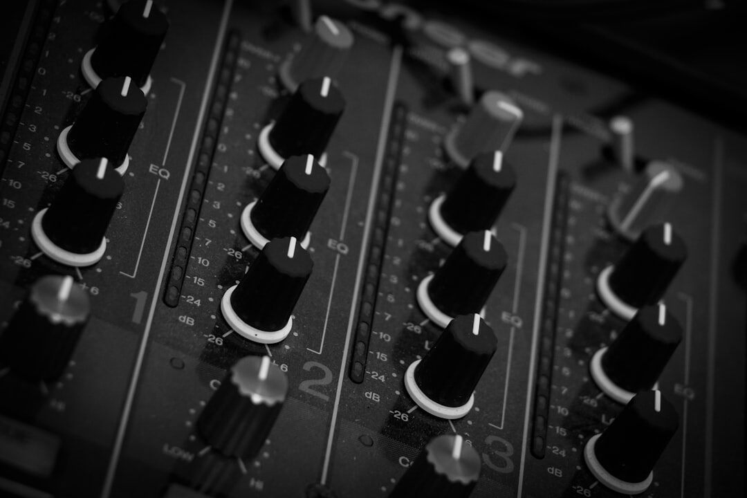 Close-up of an audio mixing soundboard with sliders and knobs